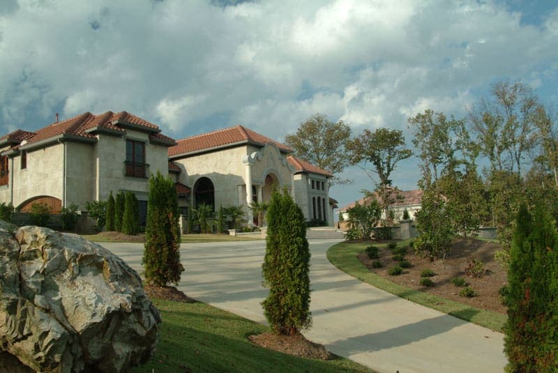 Luxurious residential landscape design by John Russell Landscape Architect featuring elegant home exterior and well-manicured yards with trees and shrubs.