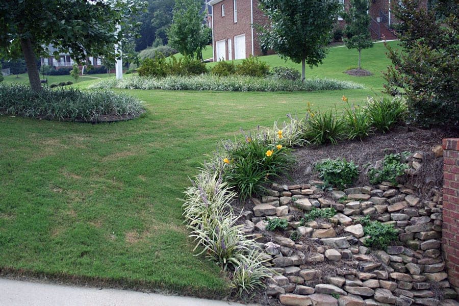 Lawn and landscape design featuring stone hillside planting with flowering perennials and shrubbery, showcasing expert landscape architecture by John Russell Landscape Architect.