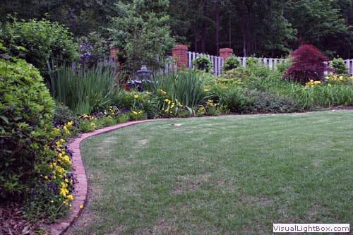 Lush garden landscape with vibrant flowers, trimmed lawn, and decorative borders created by John Russell Landscape Architect.