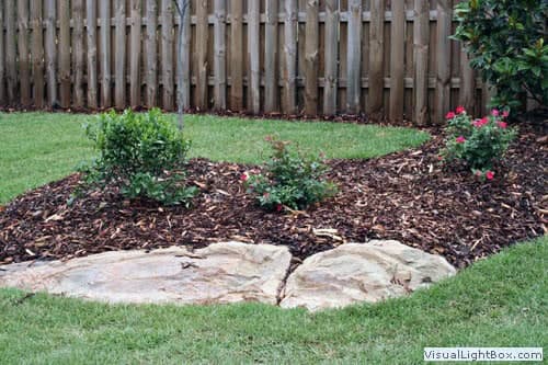 Manicured garden landscape with flower beds, mulch, stone edging, and lush lawn by John Russell Landscape Architect, specializing in custom residential landscape design and garden architecture.