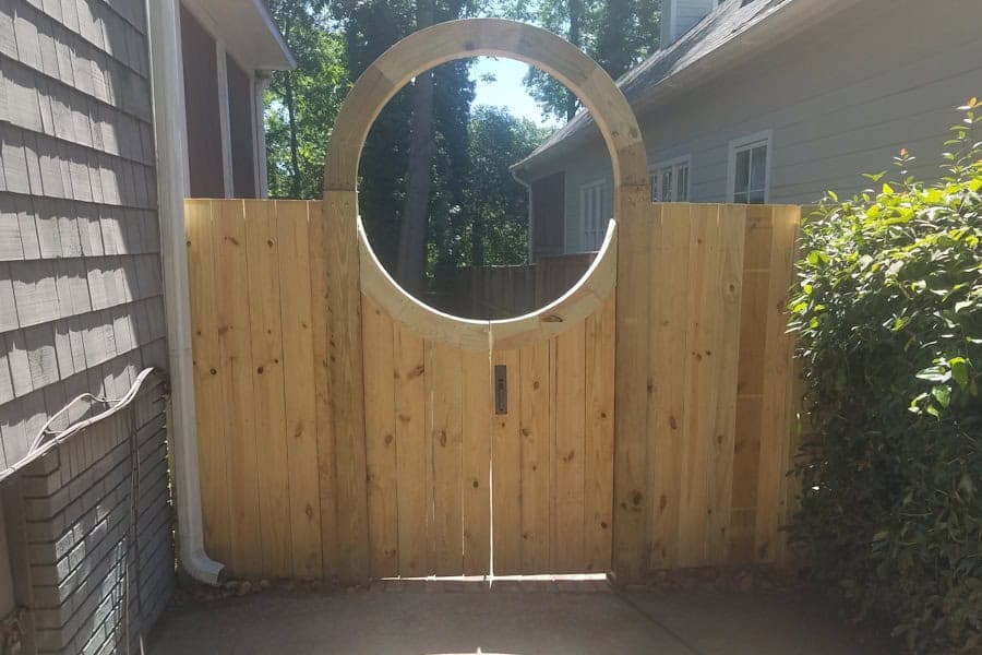 Newly built wooden backyard gate with circular window, landscape design, custom garden gate, privacy fence, outdoor landscape architecture, John Russell Landscape Architect.