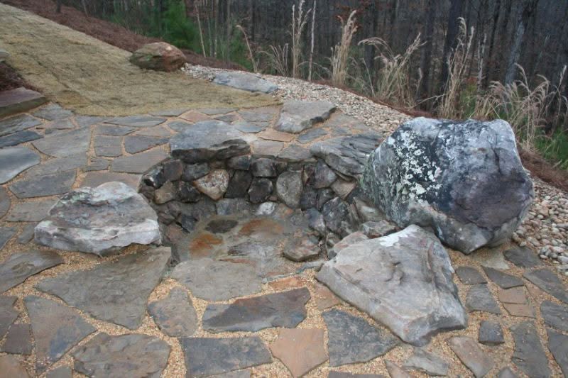 Natural stone garden fire pit with large rocks and flagstone patio by John Russell Landscape Architect.