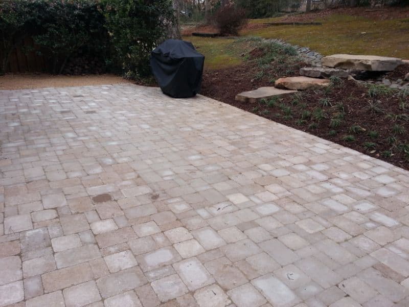 Patio with interlocking pavers in a landscaped backyard by John Russell Landscape Architect, showcasing outdoor living space design and hardscape installation.