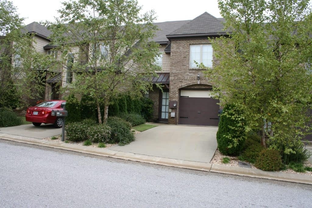 Modern brick house with landscaped front yard and driveway, showcasing professional landscape architecture by John Russell Landscape Architect in a suburban neighborhood.
