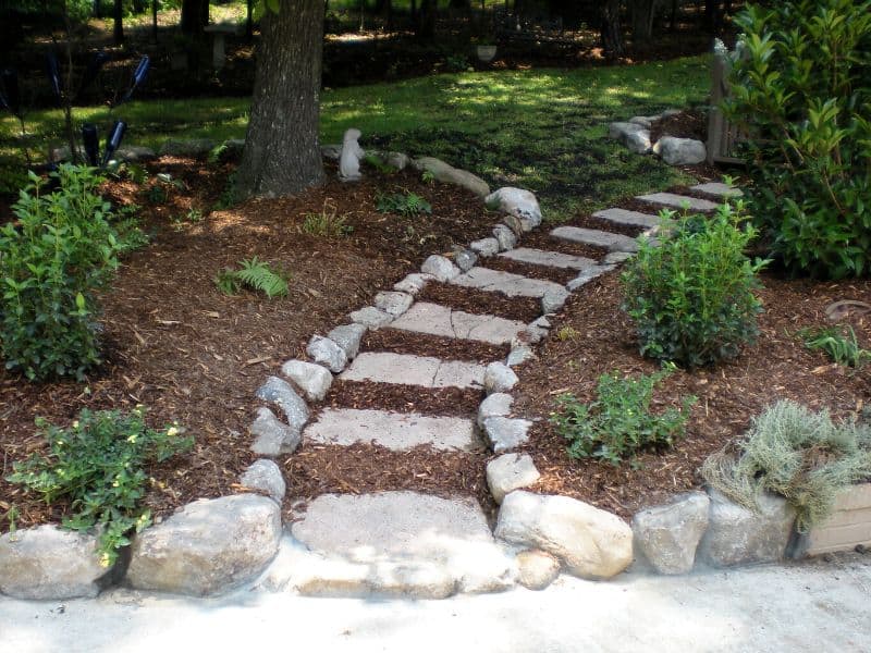 Natural stone garden pathway with stepping stones and lush greenery, designed by John Russell Landscape Architect for aesthetic outdoor spaces.