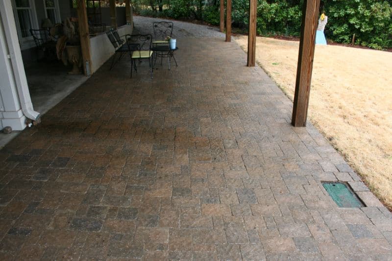 Natural stone patio with paver brick flooring, landscaped backyard, and outdoor seating area, designed by John Russell Landscape Architect for functional and aesthetic outdoor living.