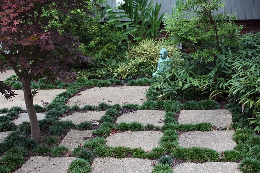 Serene garden landscape with stepping stones, lush greenery, and a peaceful Buddha statue, designed by John Russell Landscape Architect for tranquil outdoor spaces and landscape architecture excellence.