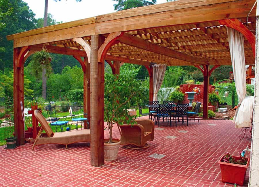 Pergola outdoor patio designed by John Russell Landscape Architect with brick flooring, cozy seating, lush greenery, and landscape planting, creating an inviting garden space for relaxation and entertaining.