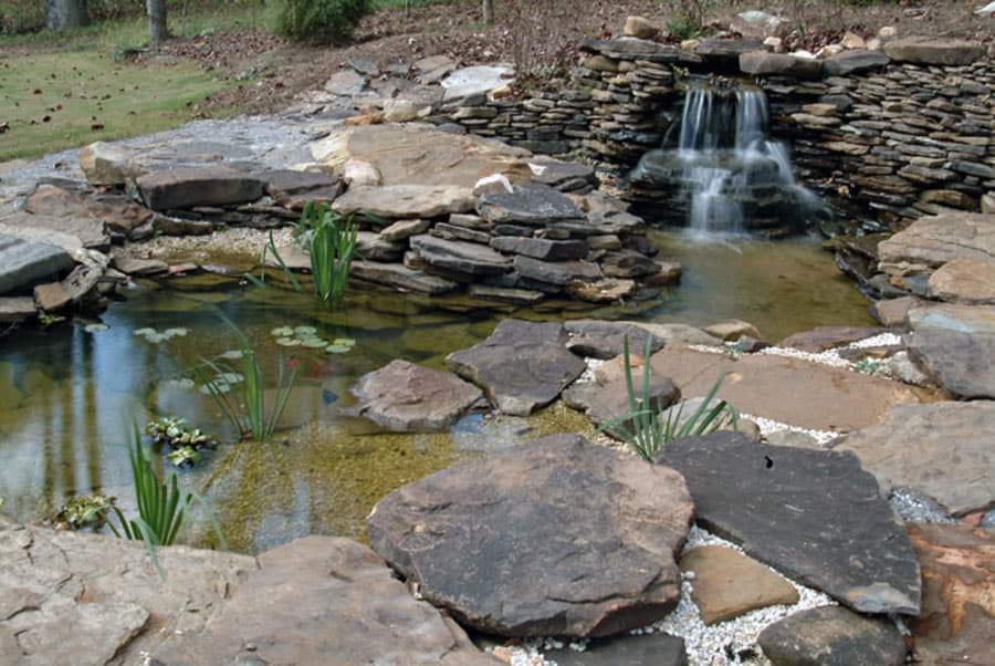 Stone water feature with waterfall and pond landscape design.