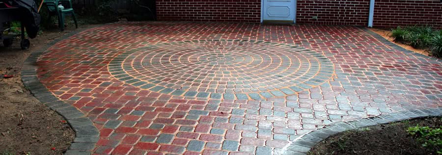 Red and gray brick circular paver driveway with curved border, landscape design by John Russell Landscape Architect in a residential yard.