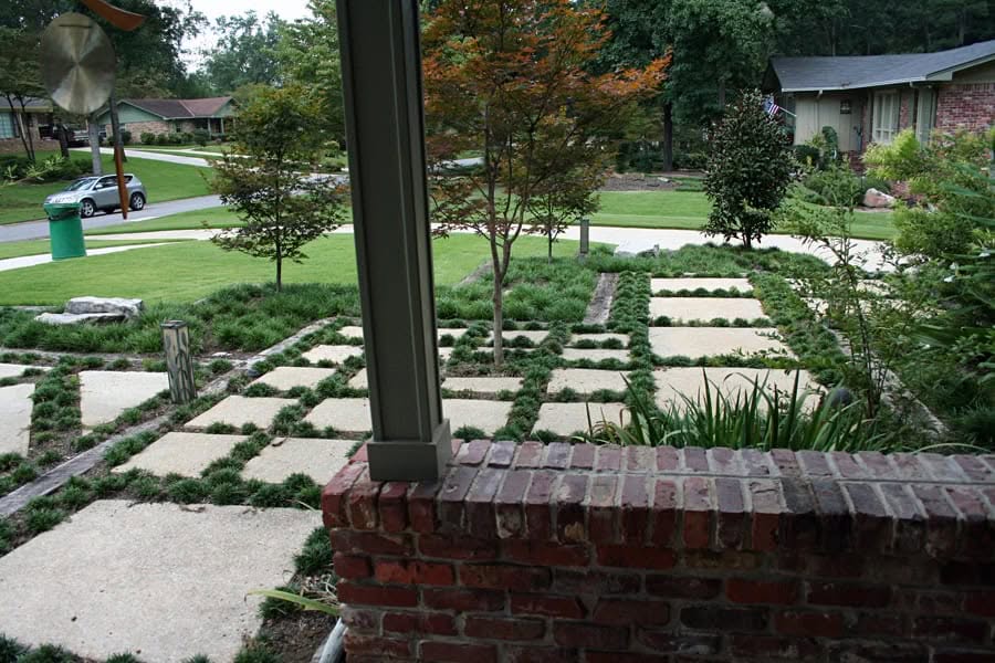 Elegant modern backyard landscape design with stone pavers, lush greenery, and mature trees, crafted by John Russell Landscape Architect for a sophisticated residential outdoor space.