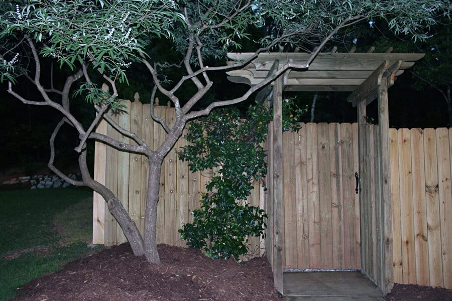 Gated garden shed entrance with wooden fencing and landscaping, landscape architecture, outdoor garden design, yard enhancement, privacy fencing, garden gate, natural wood finish, garden feature, landscape planning, exterior design, John Russell Landscape Architect.