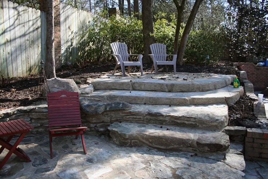 Natural stone patio with tiered steps and outdoor seating, designed by John Russell Landscape Architect for a serene backyard retreat.