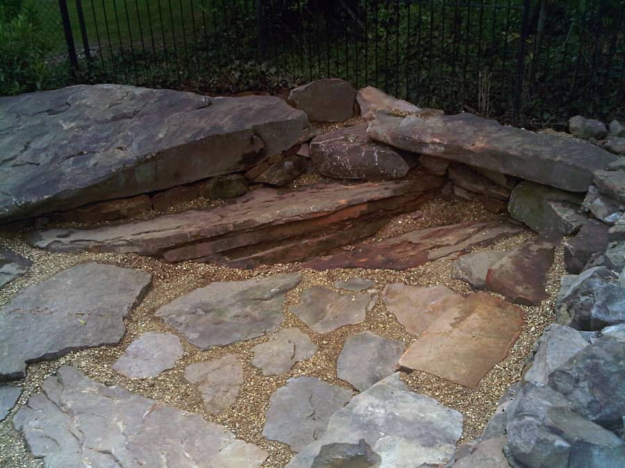 Rough natural stone fire pit design by John Russell Landscape Architect in outdoor landscaping and stonework.