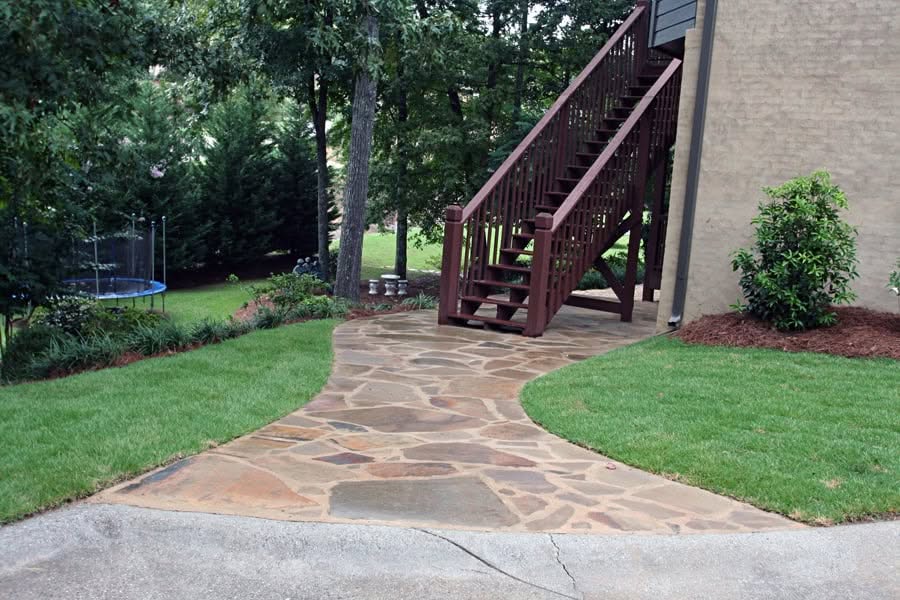 Natural stone pathway leading to a backyard staircase with lush landscaping - John Russell Landscape Architect.