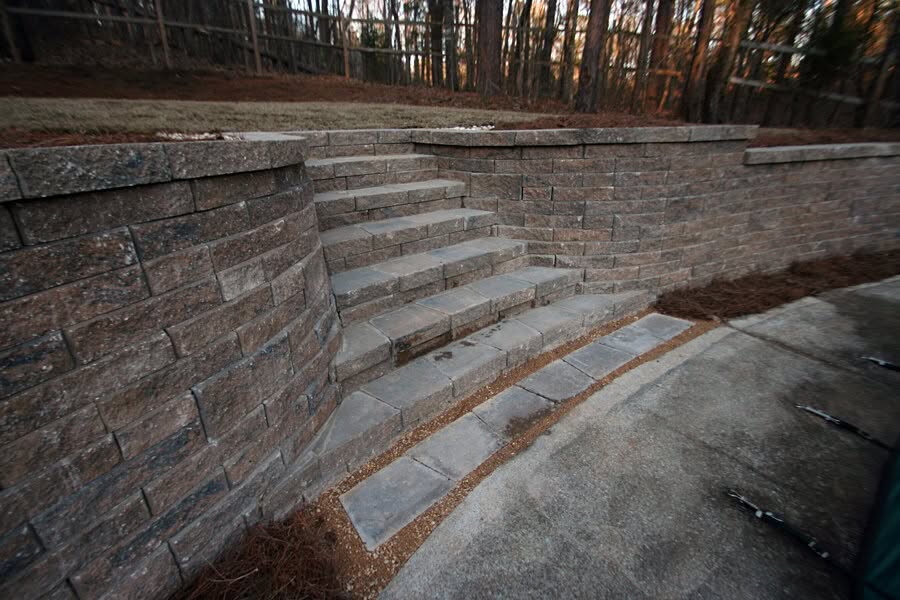Natural stone retaining wall with stairs, landscaping design by John Russell Landscape Architect, showcasing durable hardscape material and outdoor garden features in a residential landscape project.