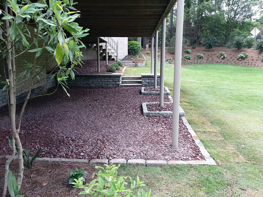 Modern backyard landscape design with mulched yard, stone border, and slope grass area, landscaped with shrubs, trees, and outdoor living space, created by John Russell Landscape Architect.