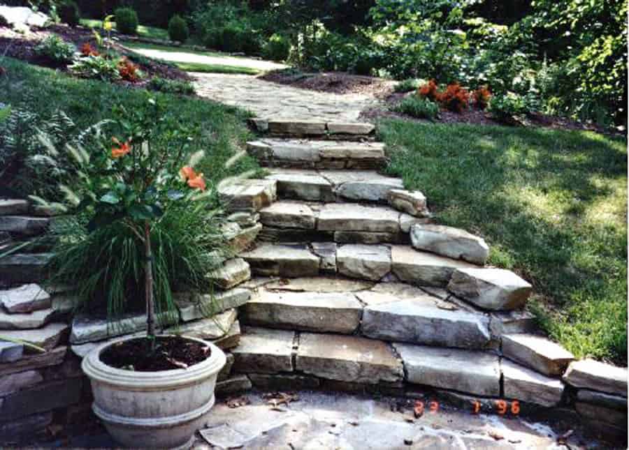 Natural stone backyard garden pathway with landscaping and lush greenery.