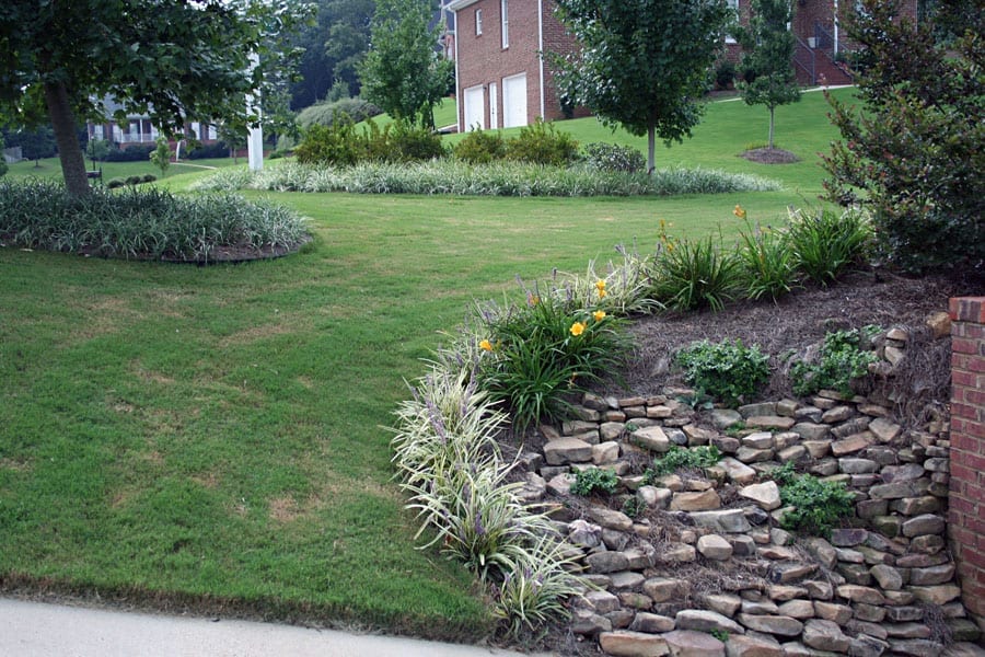 Lawn and landscape design featuring stone hillside planting with flowering perennials and shrubbery, showcasing expert landscape architecture by John Russell Landscape Architect.