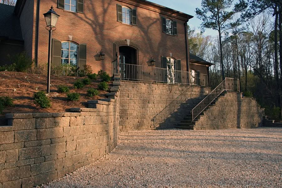 Natural stone retaining wall and landscape design by John Russell Landscape Architect, enhancing property aesthetics and functionality.