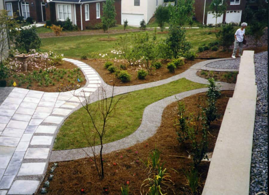 Elegant residential landscape design featuring curved pathways, lush plantings, and a modern patio by John Russell Landscape Architect, highlighting expertise in sustainable and aesthetic outdoor spaces.