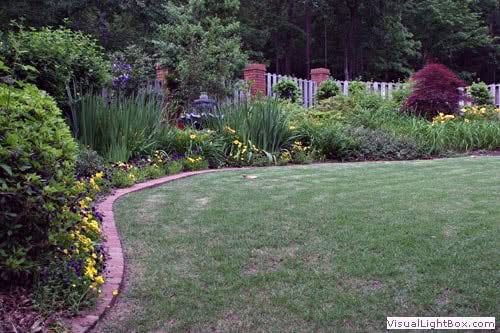 Lush garden landscape with vibrant flowers, trimmed lawn, and decorative borders created by John Russell Landscape Architect.