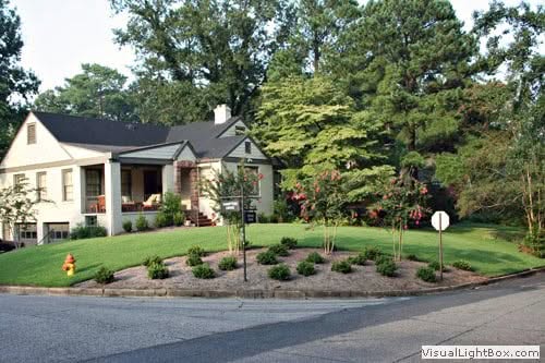 Lush residential landscape design by John Russell Landscape Architect featuring manicured lawns, colorful flowering plants, and mature trees, demonstrating expert landscape architecture.