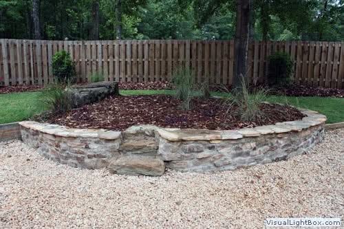 Rustic stone landscape planter with lush greenery, designed by John Russell Landscape Architect for outdoor garden enhancement and landscape architecture expertise.