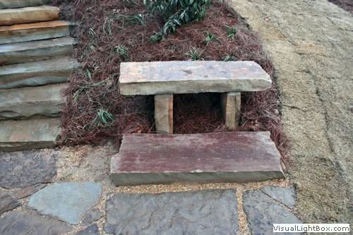 Weathered wooden garden bench with stone pathway, landscape design by John Russell Landscape Architect.