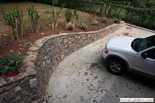 Natural stone retaining wall designed by John Russell Landscape Architect for functional and aesthetic outdoor landscaping solutions.