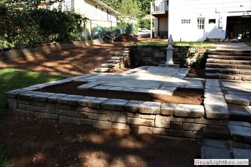 Elegant backyard paver patio with stone steps and retaining walls, designed by John Russell Landscape Architect, showcasing professional outdoor space planning and landscaping expertise.