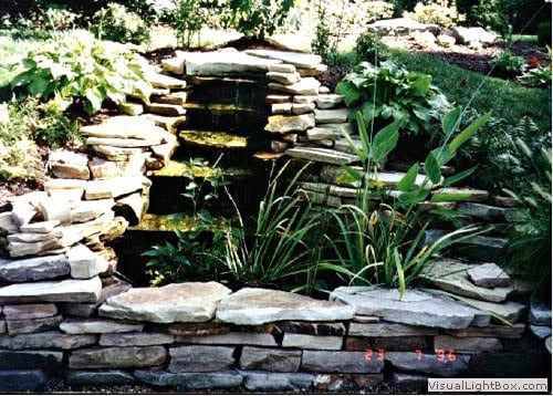 Natural stone waterfall feature in landscaped garden, designed by John Russell Landscape Architect.